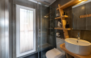 Moderne badkamer met glazen douche, houten rek en ronde wasbak bij Dome House Duplex Do Lago in Portugal.