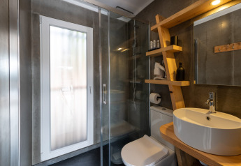 Salle de bain moderne avec douche en verre, étagères en bois et lavabo rond à Dome House Duplex Do Lago, Portugal.