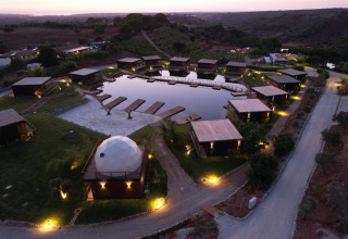 Luchtfoto van Dome House Duplex Do Lago-lodge in Wecamp Reserva Alecrim, omringd door chalets en vijver in Portugal.