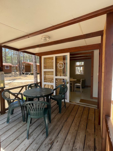 Houten veranda bij Bungalow Family met kunststof tafel en stoelen, zicht op het knusse chaletbinnen.