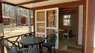 Houten veranda bij Bungalow Family met kunststof tafel en stoelen, zicht op het knusse chaletbinnen.