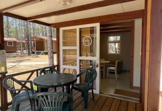 Houten veranda bij Bungalow Family met kunststof tafel en stoelen, zicht op het knusse chaletbinnen.