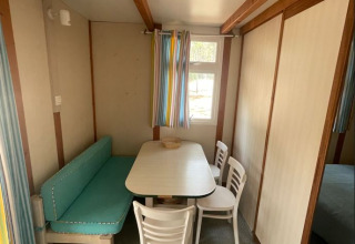 Eethoek van Bungalow Basic Family bij Wecamp Sao Miguel, Portugal, met tafel, stoelen en zitbank.