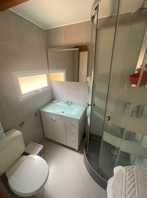 Kleine badkamer met douche, toilet, wastafel en raam in Bungalow Basic Family van Wecamp São Miguel, Portugal.