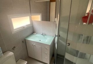 Kleine badkamer met douche, toilet, wastafel en raam in Bungalow Basic Family van Wecamp São Miguel, Portugal.