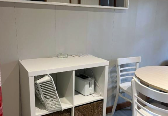 A modern lodge corner at Bungalow Basic Couple with white shelves, toaster, baskets, and a wall mirror.
