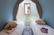 Due letti singoli in una cameretta della Coco Suite, Trasimeno Glamping Resort, Italia, con giochi e libri.