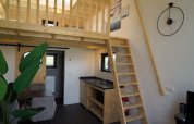Interieur van Tiny House 2+2 in Hindeloopen, Nederland, met loft, houten trap, keuken en eettafel.