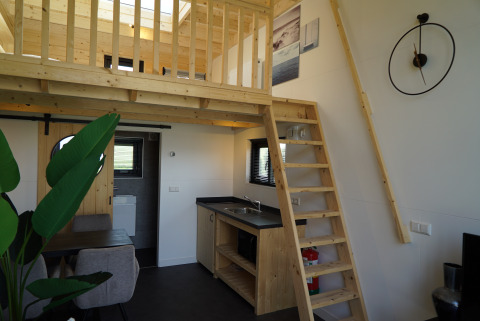 Intérieur du Tiny House 2+2 à Hindeloopen, aux Pays-Bas, avec mezzanine, escalier, cuisine et coin repas.