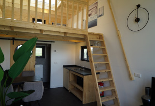 Intérieur du Tiny House 2+2 à Hindeloopen, aux Pays-Bas, avec mezzanine, escalier, cuisine et coin repas.