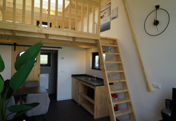 Intérieur du Tiny House 2+2 à Hindeloopen, aux Pays-Bas, avec mezzanine, escalier, cuisine et coin repas.