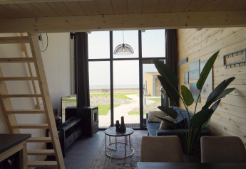 Interior of Tiny House 2+2 in Hindeloopen, Netherlands, featuring a cozy setup and large windows overlooking the sea.