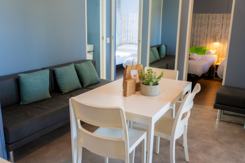 Sala moderna con mesa de comedor y sofá en Cottage Next XXL Prestige en Trasimeno Glamping Resort, Italia.