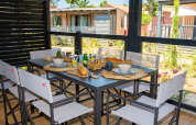 Tavolo per la colazione all'aperto con pane, succo e caffè al Cottage Next XXL Prestige, Trasimeno Glamping Resort, Italia.