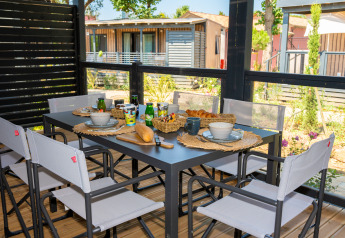 Mesa de desayuno al aire libre con pan, zumo y café en Cottage Next XXL Prestige, Trasimeno Glamping Resort, Italia.