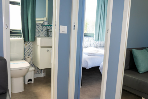 Vista del baño y dormitorio de la Cabaña Next XXL Prestige desde el pasillo en Trasimeno Glamping Resort, Italia.