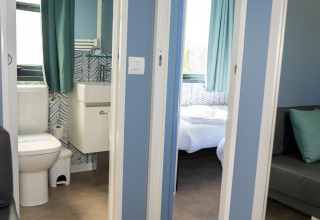 Vista del baño y dormitorio de la Cabaña Next XXL Prestige desde el pasillo en Trasimeno Glamping Resort, Italia.