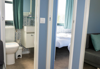 Vista del baño y dormitorio de la Cabaña Next XXL Prestige desde el pasillo en Trasimeno Glamping Resort, Italia.