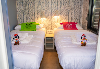 Dos camas individuales con camisetas coloridas, peluches de Goofy y luces modernas en Cottage Next XXL Prestige.