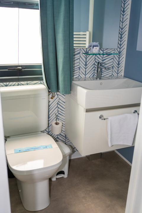 Baño moderno en Cottage Next XXL Prestige, Trasimeno Glamping Resort, Italia, con inodoro y lavabo elegantes.