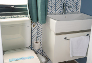 Baño moderno en Cottage Next XXL Prestige, Trasimeno Glamping Resort, Italia, con inodoro y lavabo elegantes.