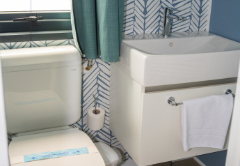 Baño moderno en Cottage Next XXL Prestige, Trasimeno Glamping Resort, Italia, con inodoro y lavabo elegantes.