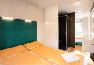 Camera da letto del Cottage Next XL Panorama presso Trasimeno Glamping Resort, Italia, con arredo moderno.