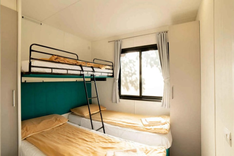 Camera da letto con letto a castello e due singoli nel Cottage Next XL Panorama al Trasimeno Glamping Resort, Italia.