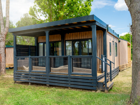Foto esterna del Cottage Next XL Panorama, un moderno lodge in legno con veranda coperta e grandi finestre.