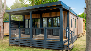 Foto esterna del Cottage Next XL Panorama, un moderno lodge in legno con veranda coperta e grandi finestre.