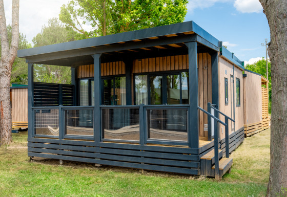 Foto esterna del Cottage Next XL Panorama, un moderno lodge in legno con veranda coperta e grandi finestre.