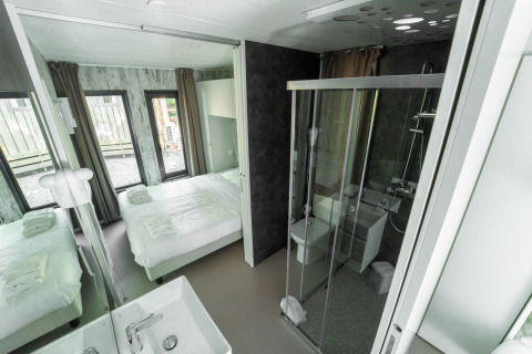 Camera da letto e bagno moderni con grandi finestre presso Cottage Next XL Panorama, Trasimeno Glamping Resort, Italia.