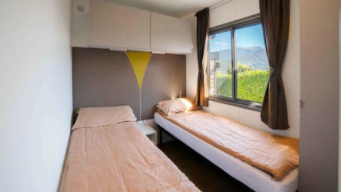 Due letti singoli con lenzuola beige in una luminosa camera del Cottage Next XL Superior, Trasimeno Glamping Resort, Italia.