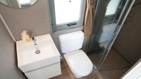 Bagno moderno e compatto con lavandino, WC e doccia nel Cottage Next XL Superior del Trasimeno Glamping Resort, Italia.