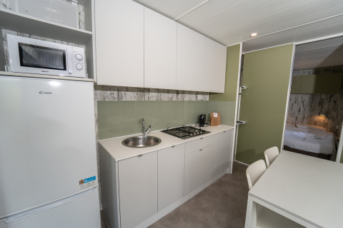 Cocina moderna y comedor en una Cottage Next XL Loggia Laguna del Trasimeno Glamping Resort en Italia.