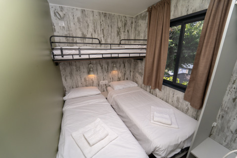 Habitación con dos camas individuales y una litera superior en Cottage Next XL Loggia Laguna, Trasimeno Glamping Resort.