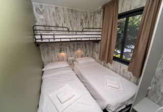 Habitación con dos camas individuales y una litera superior en Cottage Next XL Loggia Laguna, Trasimeno Glamping Resort.