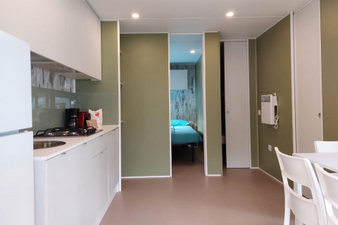 Cocina y comedor modernos en la Cottage Next XL Loggia del Trasimeno Glamping Resort en Italia, con vista al dormitorio.