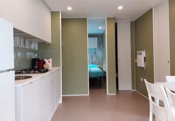 Cocina y comedor modernos en la Cottage Next XL Loggia del Trasimeno Glamping Resort en Italia, con vista al dormitorio.
