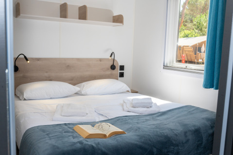 Dormitorio acogedor en Cottage Next XL Country, Trasimeno Glamping Resort, Italia, con cama doble y ventana.