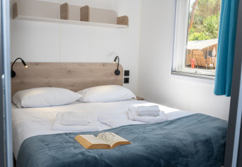 Dormitorio acogedor en Cottage Next XL Country, Trasimeno Glamping Resort, Italia, con cama doble y ventana.