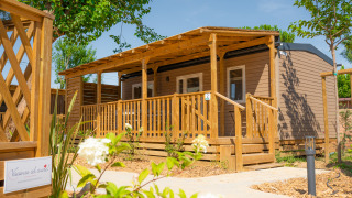 Modern houten lodge Cottage Next XL Mercure met grote veranda en omgeven door groen op een zonnige dag.