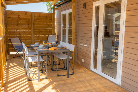 Terraza exterior en Cottage Next XL Mercure, Trasimeno Glamping Resort, con mesa y sillas para comer al aire libre.
