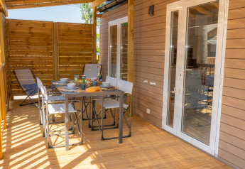 Terraza exterior en Cottage Next XL Mercure, Trasimeno Glamping Resort, con mesa y sillas para comer al aire libre.