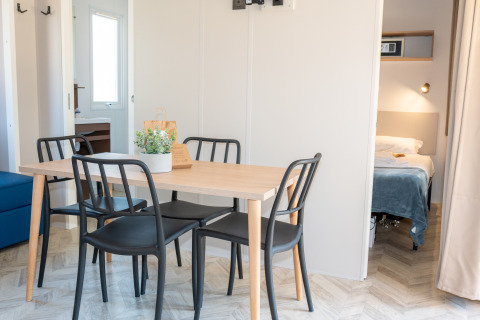 Comedor luminoso con sillas negras y mesa de madera en Cottage Next XL Mercure, Trasimeno Glamping Resort.