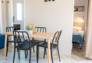 Comedor luminoso con sillas negras y mesa de madera en Cottage Next XL Mercure, Trasimeno Glamping Resort.