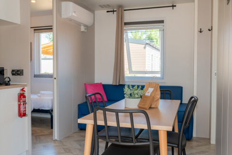 Interior del alojamiento Cottage Next XL Mercure con mesa, sofá y dormitorio en Trasimeno Glamping Resort.