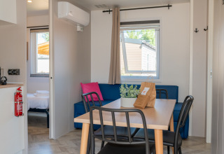 Interior del alojamiento Cottage Next XL Mercure con mesa, sofá y dormitorio en Trasimeno Glamping Resort.