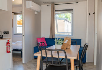 Interior del alojamiento Cottage Next XL Mercure con mesa, sofá y dormitorio en Trasimeno Glamping Resort.