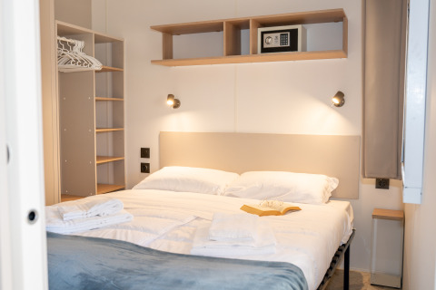 Dormitorio moderno en Cottage Next XL Mercure, Trasimeno Glamping Resort, con cama doble y armario abierto.